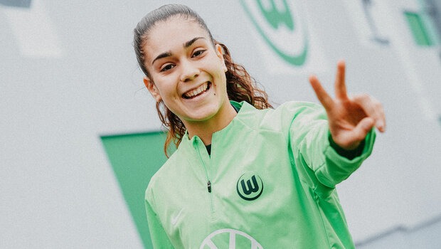 VfL-Wolfsburg-Spielerin Arias lächelt in die Kamera lächelt in die Kamera und formt mit ihrer Hand ein Peace Zeichen.