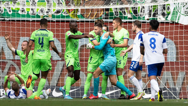 VfL Wolfsburg Keeper wird von der Mannschaft gefeiert, nachdem er einen Treffer verhindert hat.