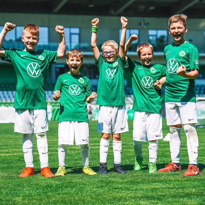 Kinder freuen sich in grün weißen Trikots bei einem Event der Fußballschule des VfL Wolfsburg.