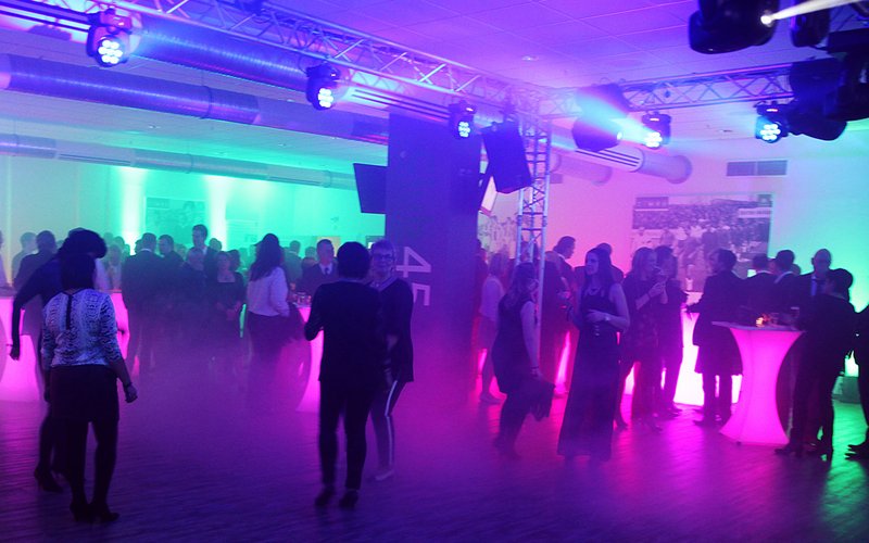 Bei einem Event des VfL Wolfsburg stehen Personen um Stehtische herum oder tanzen.