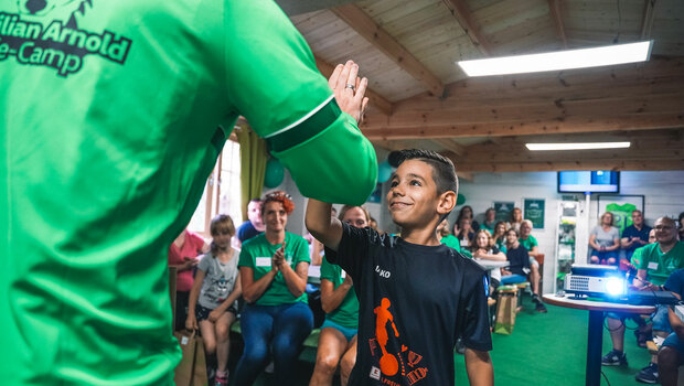 Ein Junge aus dem Wölfe Camp klatscht bei Namensgeber des Camps und VfL Wolfsburg Kapitän Maximilian Arnold ein und freut sich.