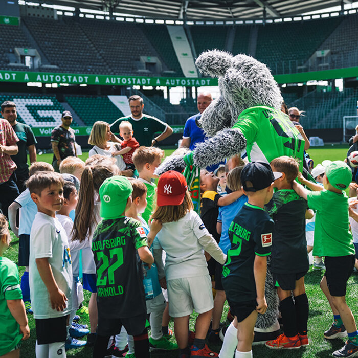 Die Kinder versammeln sich auf dem Platz der Volkswagen Arena um Wölfi, dem Maskottchen des VfL Wolfsburg.