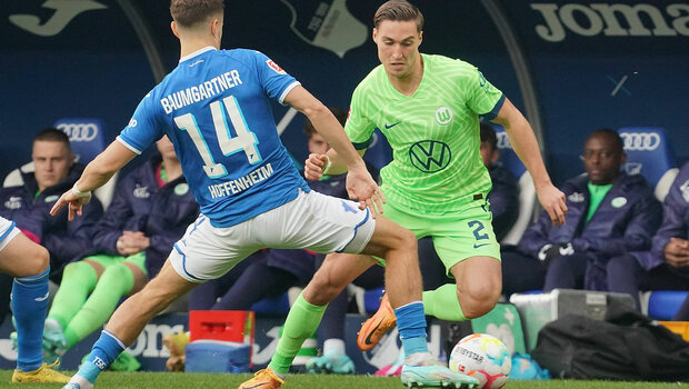 VfL-Wolfsburg-Spieler Kilian Fischer im Dribbling mit dem Ball gegen einen Spieler von Hoffenheim.
