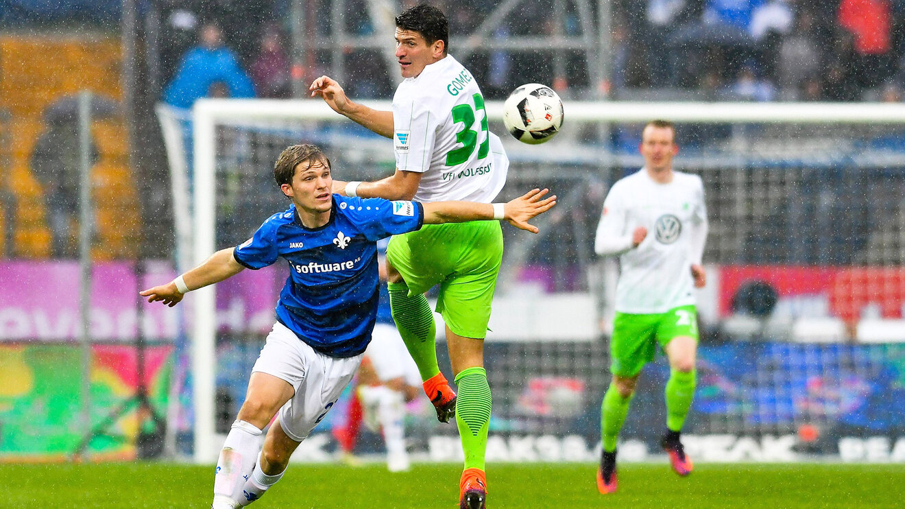 Mario Gomez vom VfL Wolfsburg dreht sich nach dem Ball um und wird von einem Gegner zur Seite geschoben. 