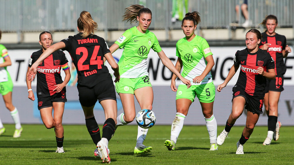 VfL Wolfsburg Spielerin Brand setzt sich im Kampf um den Ball gegen eine Gegnerin durch, im Hintergrund ist ihre Kollegin Oberdorf zu sehen.