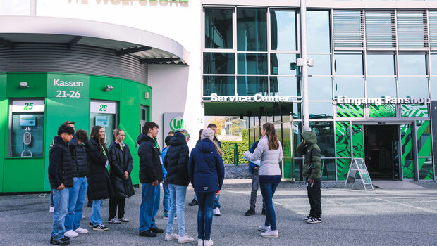 Die Teilnehmenden am VfL-Wolfsburg-Zukunftstag stehen vor dem Fanhaus.