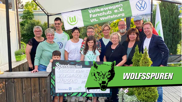 Der Volkswagen Fanclub des VfL Wolfsburg überreicht einen Spendencheck. Davor ist die Grafik "Wolfsspuren" eingeblendet.