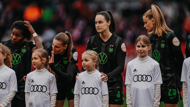 Die Spielerinnen des VfL Wolfsburg stehen hinter den Einlaufkindern.