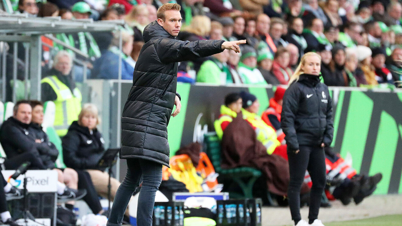 Wölfinnen Trainer Stroot steht am Spielfeldrand und ruft Anweisungen auf den Platz.