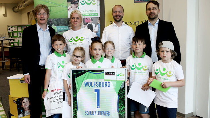 Dr. Tim Schumacher mit den Offiziellen und den Gewinnern des VfL-Schulschreibwettbewerbs. 
