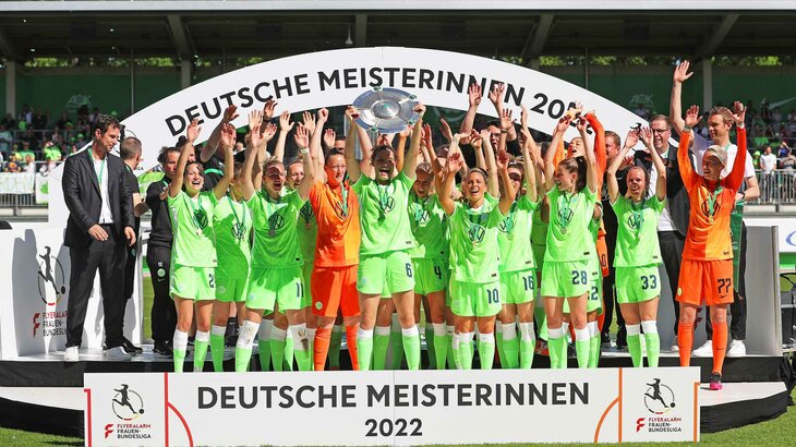 Die Spielerinnen des VfL Wolfsburg feiern mit erhobenen Händen und der Meisterschale.