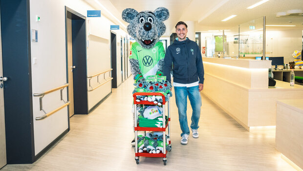 VfL-Wolfsburg-Spieler Kilian Fischer besucht gemeinsam mit Wölfi das Kinderkrankenhaus. Dort verteilen sie Wölfi-Kuscheltiere und Accessories. 