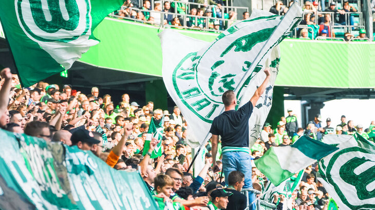 Die Fans des VfL Wolfsburg wedeln mit ihren Fahnen.