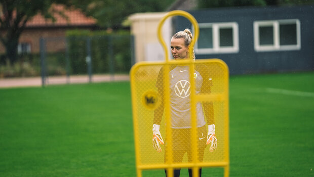 VfL-Wolfsburg-Torhüterin Merle Frohms steht hinter einer Figur im Training.