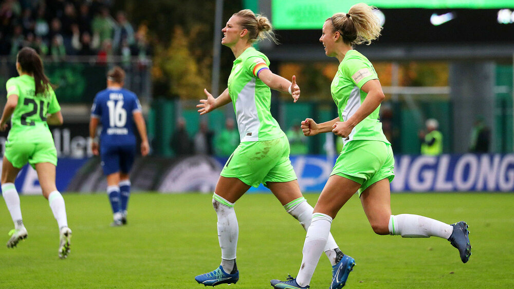 Alexandra Popp vom VfL Wolfsburg läuft jubelnd mit beiden Armen zur Seite ausgestreckt neben ihrer Mitspielerin Lena Lattwein über das Spielfeld.