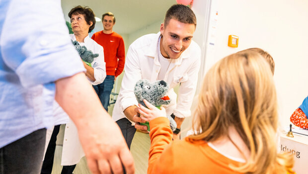VfL-Wolfsburg-Spieler Kilian Fischer bringt ein Kind in der Kinderklinik zum Lächeln.