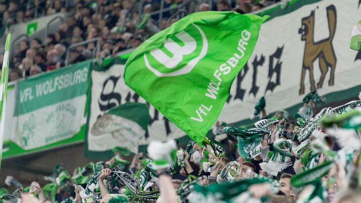 Fans des VfL Wolfsburg schwenken Fahnen.