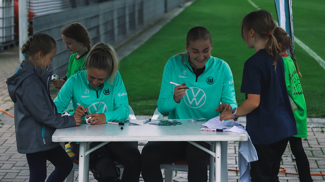 VfL-Wolfsburg-Spielerinnen Rebecka Blomqvist und Camilla Küvers geben kleinen Mädchen Autogramme.