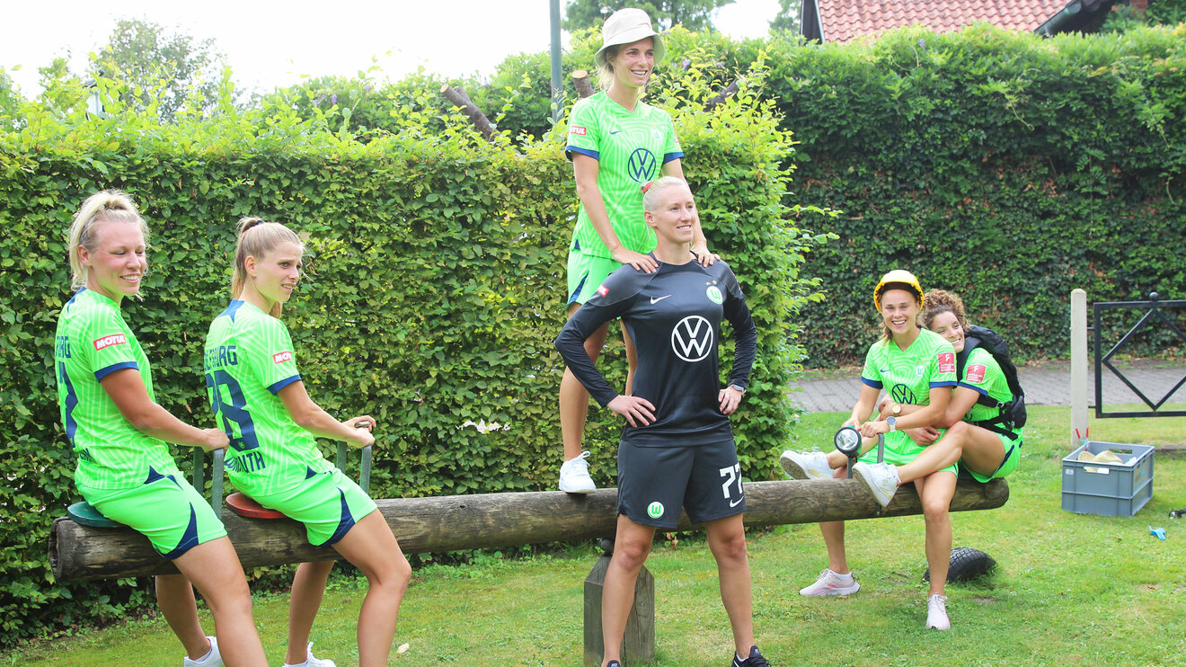 Die Spielerinnen des VfL Wolfsburg posieren auf einer Holzwippe,