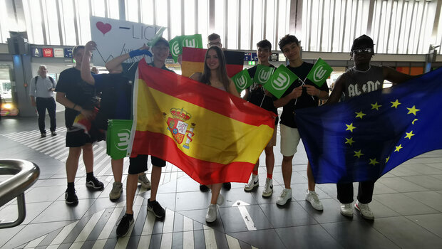 Ein Gruppenbild von Jugendlichen, die Flaggen und Fahnen vom VfL Wolfsburg in den Händen halten.