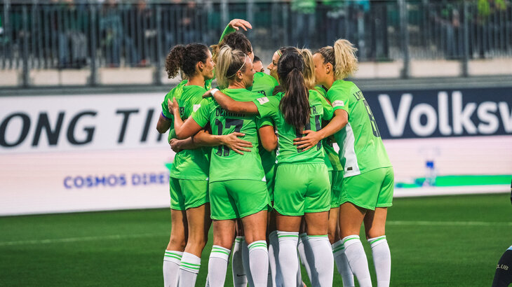 Die Frauen des VfL Wolfsburg bilden einen Teamkreis auf dem Spielfeld.