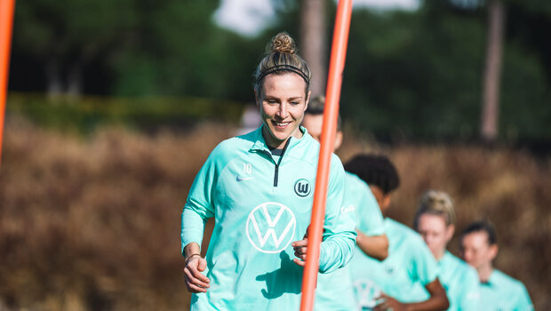 Svenja Huth vom VfL Wolfsburg trainiert mit einem Lächeln, hinter ihr befinden sich ihre Teamkolleginnen.