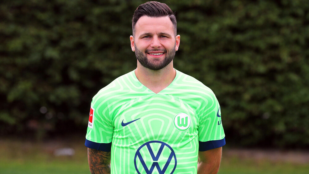 VfL Wolfsburg Spieler Steffen posiert im Trikot und lächelt in die Kamera.