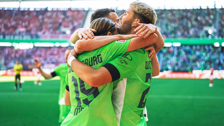 Die VfL Wolfsburg-Spieler Jonas Wind, Yannick Gerhardt und Patrick Wimmer umarmen sich fest nach dem Tor.