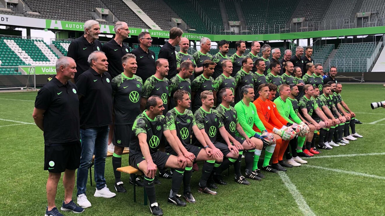 Die Traditionsmannschaft des VfL Wolfsburg macht auf dem Platz ein Mannschaftsfoto.