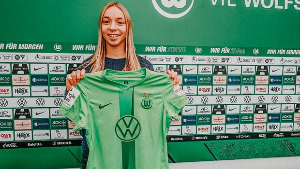 Neuzugang Ella Peddemors hält ein Heimtrikot des vfL Wolfsburg hoch..
