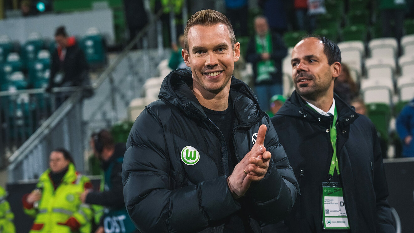 VfL-Wolfsburg-Tariner Tommy Stroot lacht und klatscht in die Hände.
