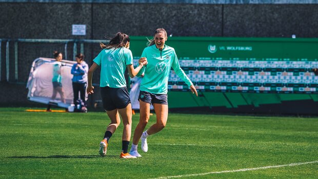VfL-Wolfsburg-Spielerin Jule Brand schlägt im Training mit einer Mitspielerin im Laufen ein.