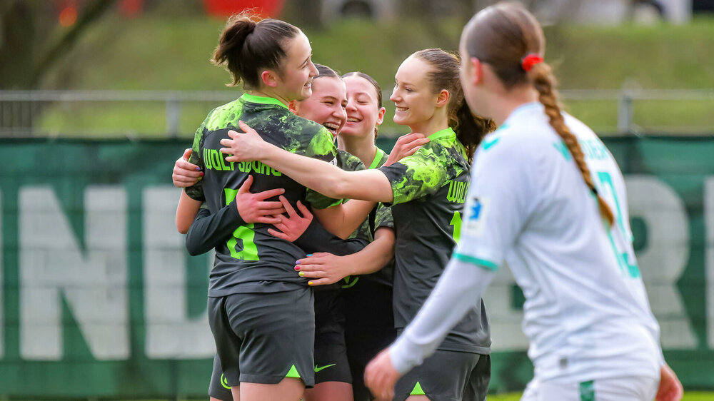 Die U17 Juniorinnen des VfL Wolfsburg umarmen sich und jubeln auf dem Spielfeld.