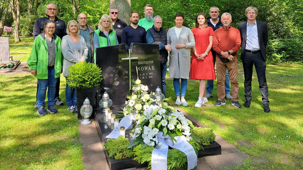 VfL Wolfsburg Geschäftsführer Meeske steht zusammen mit den Fanbeauftragten und weiteren Personen am Grab von Krzysztof Nowak.