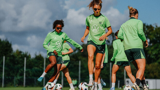 Die VfL Wolfsburg-Spielerinnen laufen mit Ball und Piratenmaske auf dem Trainingsplatz.