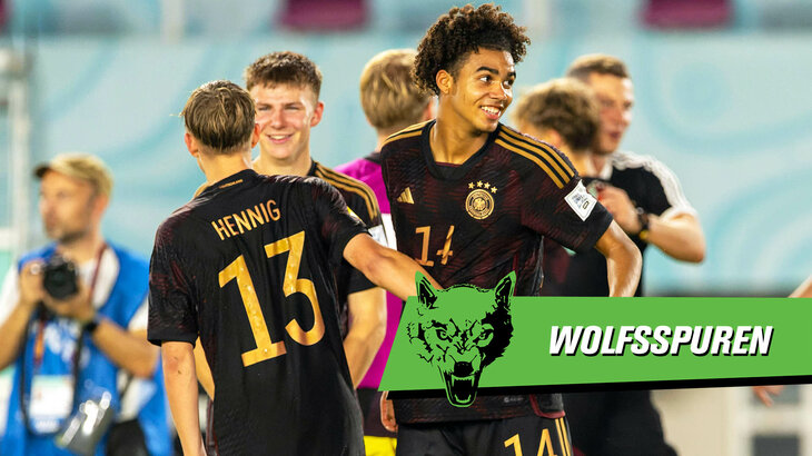 VfL Wolfsburg Spieler Odogu steht mit Mitspielern im Trikot der Nationalmannschaft auf dem Feld.