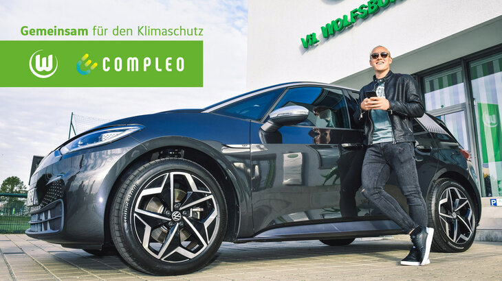 VfL-Wolfsburg-Spieler Schlager mit einem e-Auto compleo.
