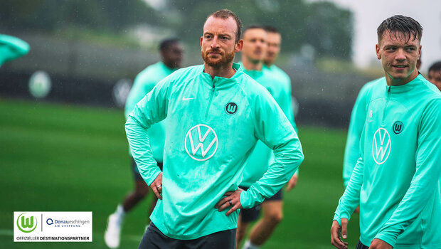VfL Wolfsburg Spieler Arnold steht mit den Händen auf den Hüften im Regen auf dem Trainingsplatz.