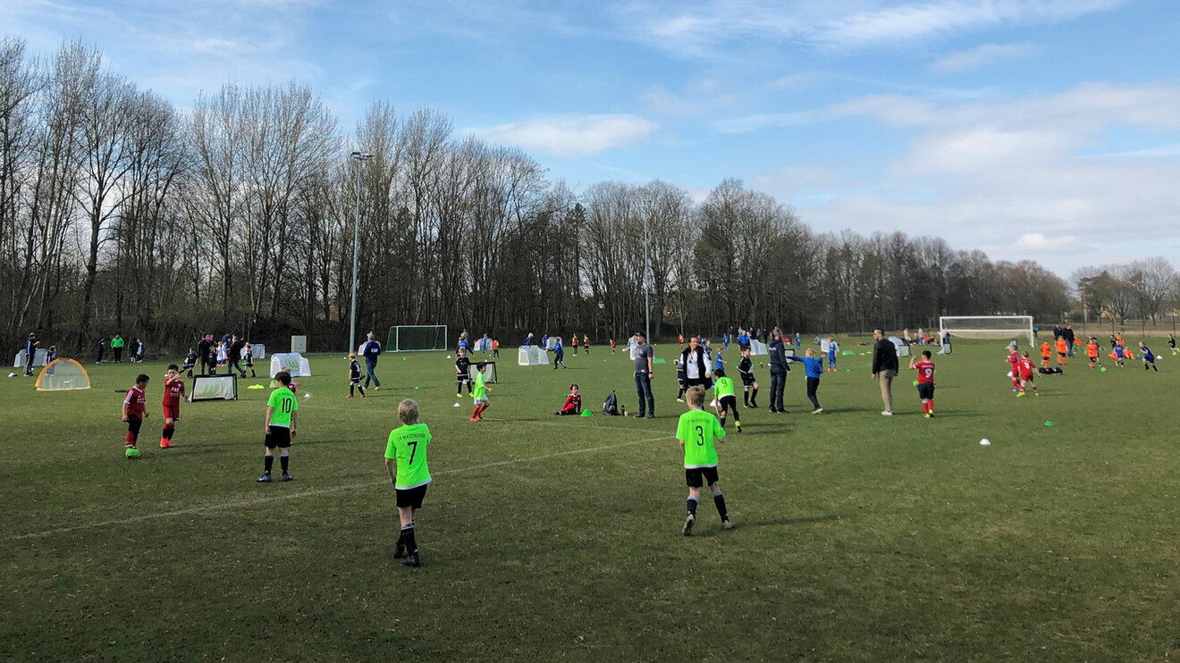 Kinder spielen beim Kinderfußballtag des VfL Wolfsburg Fußball auf mehreren Spielfeldern.