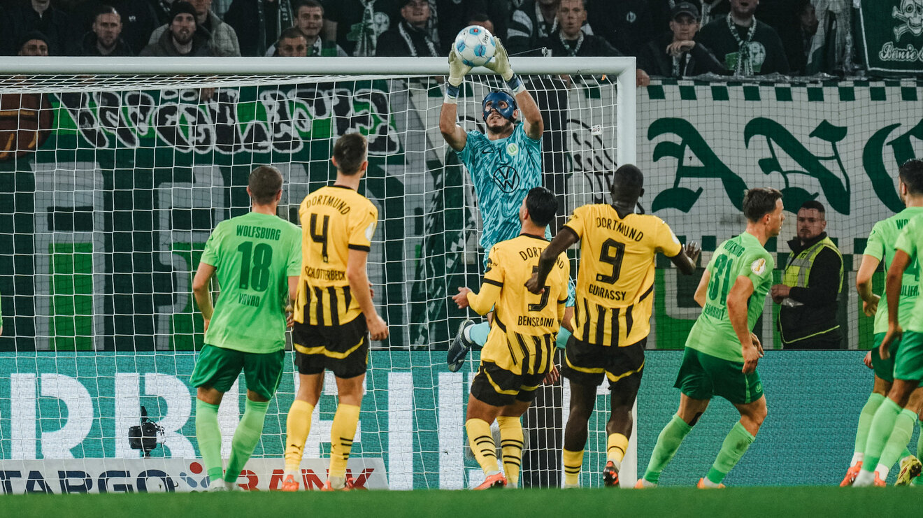 VfL Wolfsburg Torwart Kamil Grabara springt im Spiel gegen Dortmund hoch und fischt einen Ball vor dem Tor aus der Luft.