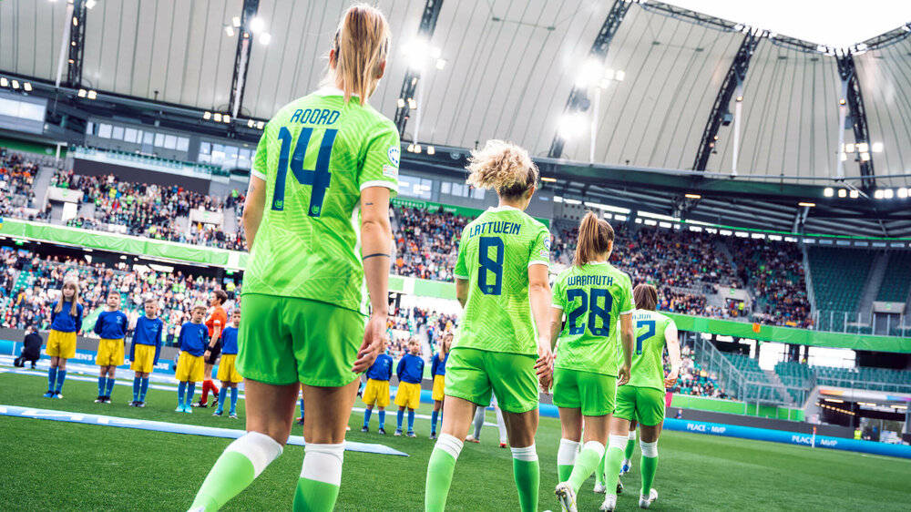 VfL Wolfsburg Spielerinnen Roord, Lattwein und Wassmuth laufen in die Volkswagen Arena ein, das Foto zeigt alle Damen von hinten hintereinander laufend