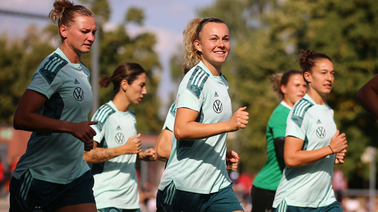 Die VfL Wolfsburg-Spielerinnen Alex Popp, Lena Lattwein und Felicitas Rauch laufen im Shirt der Nationalmannschaft.