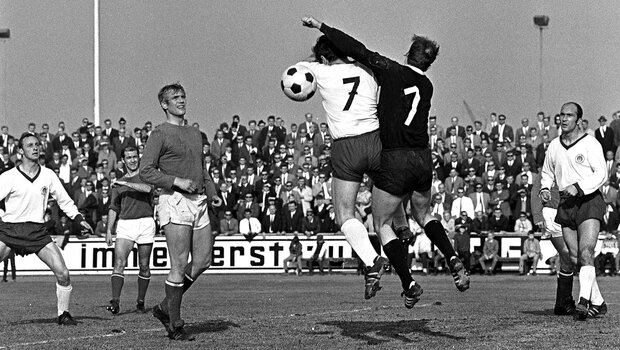 Ein historisches schwarz-weiß-Bild eines Zweikampfes in der Luft bei einer Partie des VfL Wolfsburg gegen den FC St. Pauli.