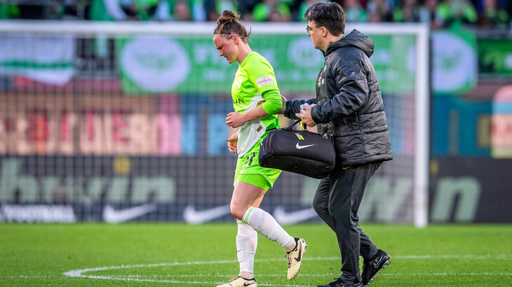 Marina Hegering, Spielerin des VfL Wolfsburg, läuft mit dem Mannschaftsarzt vom Platz und schaut zu Boden.