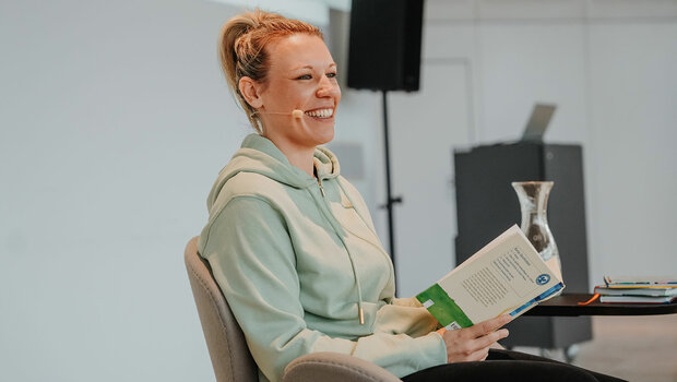 Die VfL-Wolfsburg-Spielerin Kristin Demann liest aus einem Buch vor.