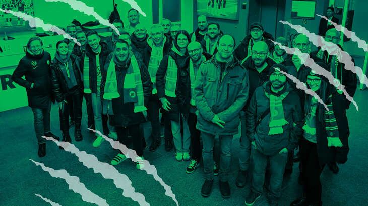 VfL-Wolfsburg-Legende Roy Präger und Mitarbeiter von Volkswagen stehen zusammen und lächeln.
