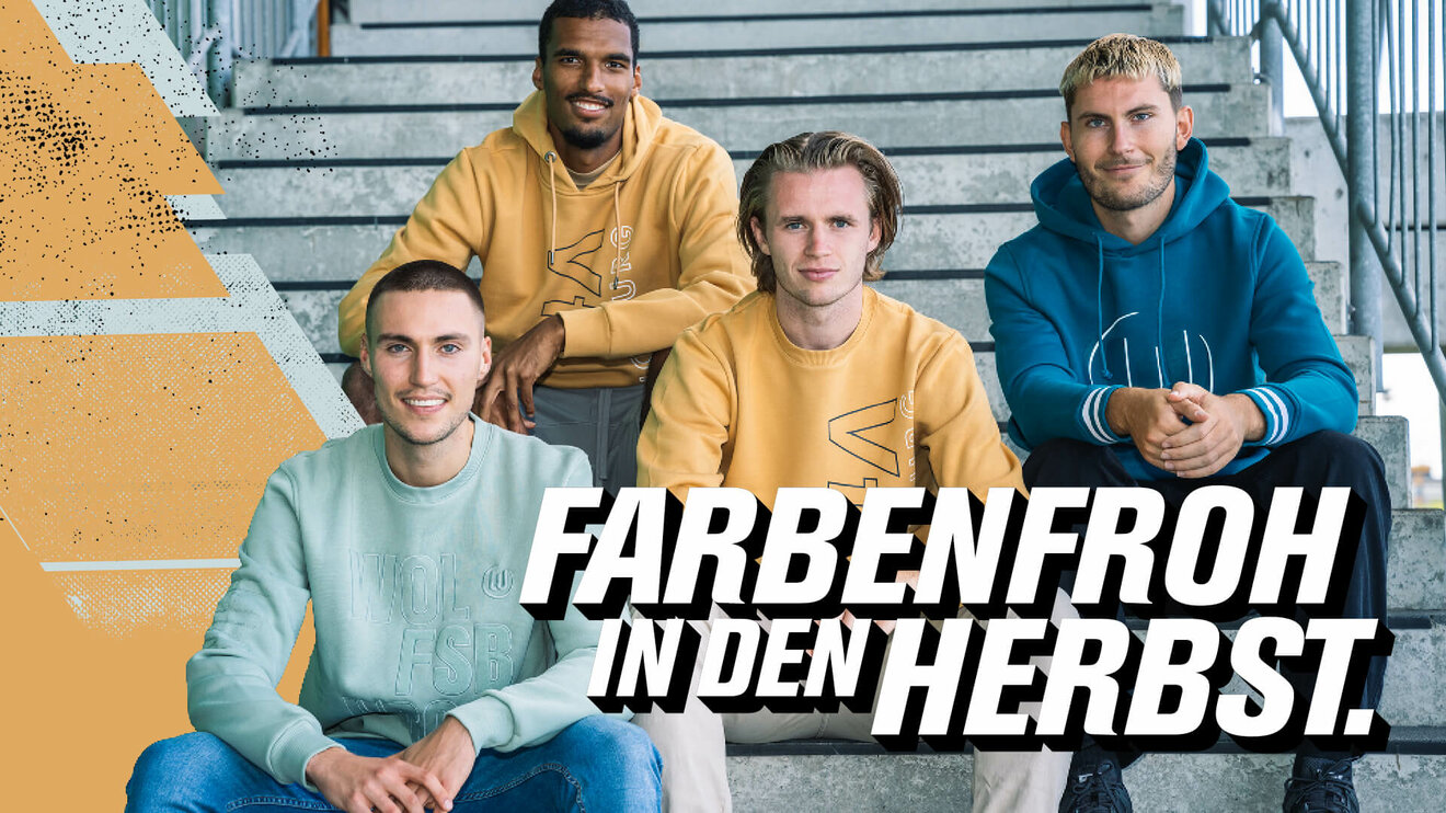 Die VfL-Wolfsburg-Spieler sitzen in den Pullovern der Herbstkollektion auf einer Treppe