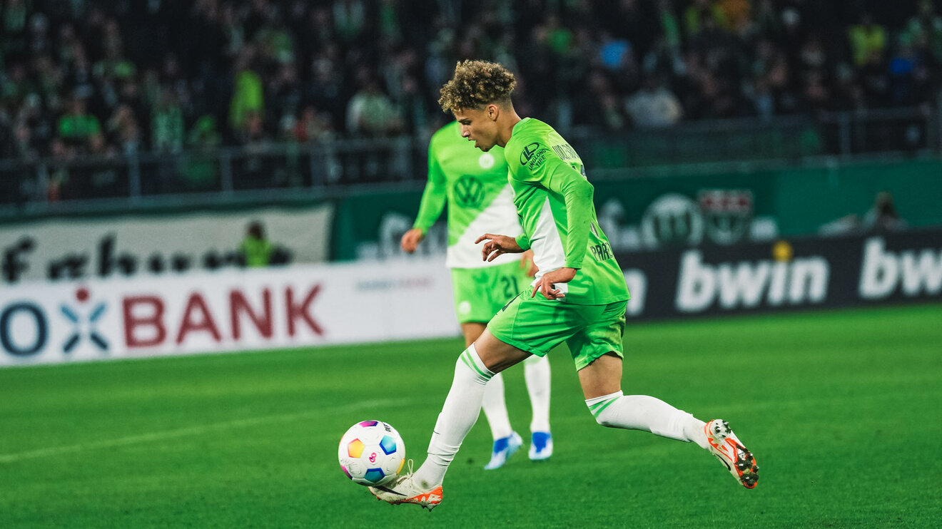 Kevin Paredes vom VfL Wolfsburg läuft mit dem Ball vor ihm am linken Fuß.