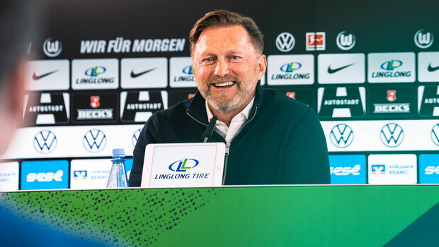 VfL Trainer Ralph Hasenhüttl sitzt bei der Pressekonferenz am Mikrofon und lacht.