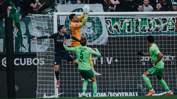 VfL-Wolfsburg-Torwart Marius Müller springt in die Luft und Fängt den Ball.